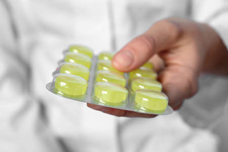 Woman holding blister with cough drops, closeup