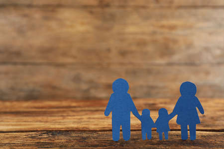 Paper family figure on wooden table, space for text. child adoption conceptの写真素材