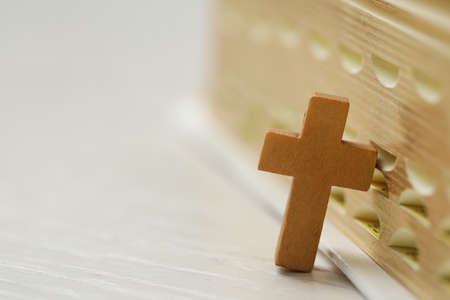 Christian cross near Bible on white wooden table, closeup. Space for textの写真素材