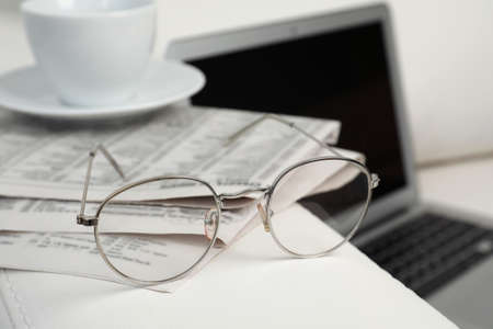 Newspapers, glasses and cup of drink on armrest indoorsの写真素材