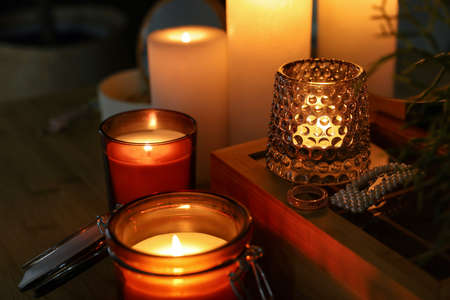 Lit candles on wooden dressing table in dark roomの写真素材