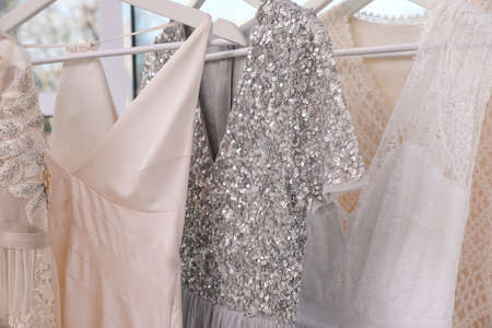 Hangers with different beautiful dresses in atelier, closeupの写真素材