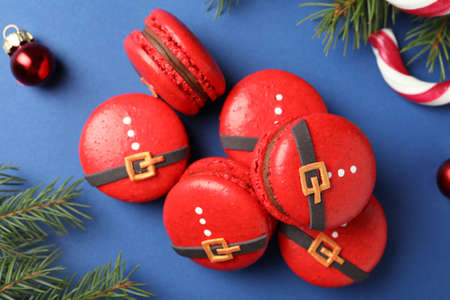 Pile of beautifully decorated Christmas macarons on blue background, flat layの写真素材