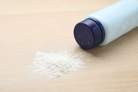 Bottle and scattered dusting powder on wooden background. baby cosmetic productの写真素材