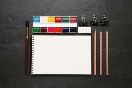 Flat lay composition with blank sketchbook on black slate table. Space for textの写真素材