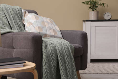 Living room interior with comfortable gray armchair, pillow and plaid