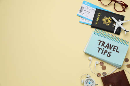 Notebook with phrase Travel Tips and tourist items on yellow background, flat lay. Space for textの写真素材