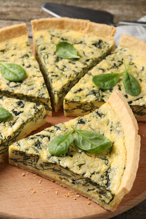 Cut delicious spinach pie on wooden board, closeupの写真素材