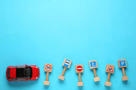 Many different miniature road signs and car on light blue background, flat lay with space for text. driving schoolの写真素材