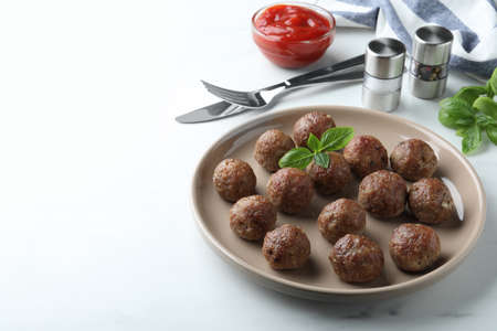 Tasty cooked meatballs with basil on white table. Space for textの写真素材
