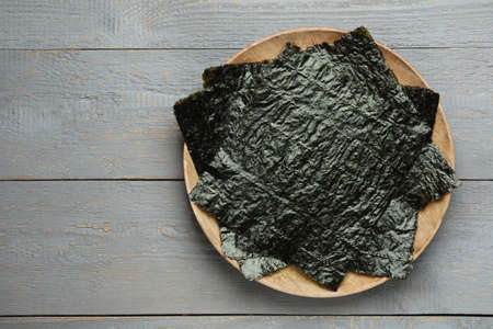Dry nori sheets on gray wooden table, top view. Space for text