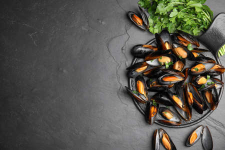 Serving board with cooked mussels and parsley on slate table, flat lay. Space for textの写真素材