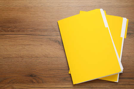 Yellow files with documents on wooden table, top view. Space for textの写真素材