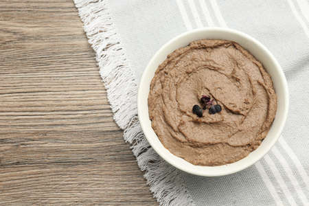 Tasty liver pate with herb in bowl on wooden table, top view. Space for text