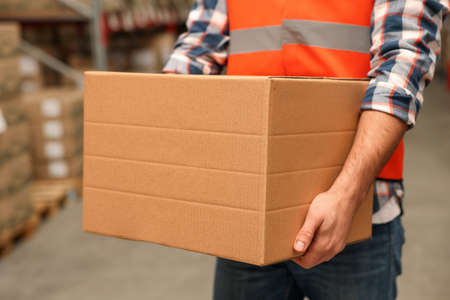 Worker with cardboard box in warehouse, closeup. Wholesaling