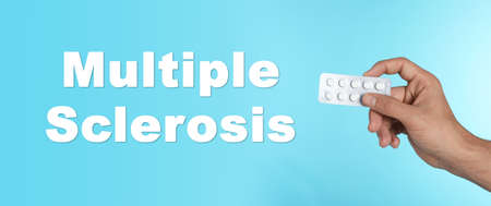 Multiple sclerosis treatment. Man holding pills on light blue background, closeupの写真素材