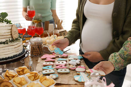 Pregnant woman and her friends taking delicious treats at baby shower party, closeupの写真素材