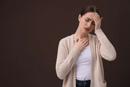 Woman suffering from headache on brown background, space for text. cold symptomsの写真素材
