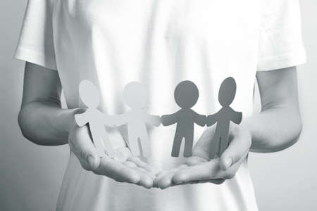 Young woman holding paper people, closeup. unity concept