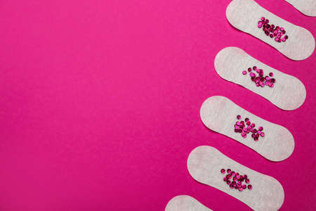 Sanitary pads with sequins on pink background, flat lay and space for text. menstrual cycleの写真素材