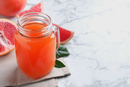 Tasty freshly made grapefruit juice on white marble table. Space for textの写真素材