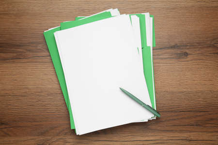 Light green files with blank sheets of paper and pen on wooden table, top view. space for designの写真素材