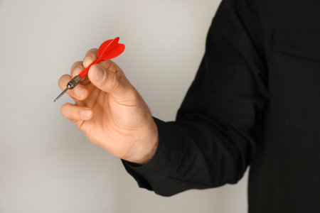 Man holding red dart on light background, closeupの写真素材