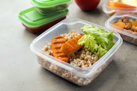 Set of plastic containers with fresh food on light gray table