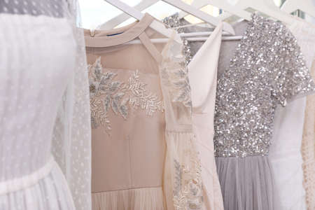 Hangers with different beautiful dresses in atelier, closeupの写真素材