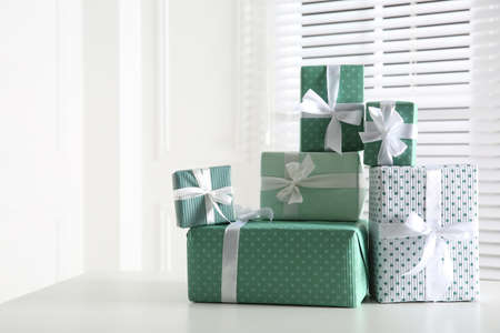 Heap of wrapped gift boxes on white table, space for text. happy holidays