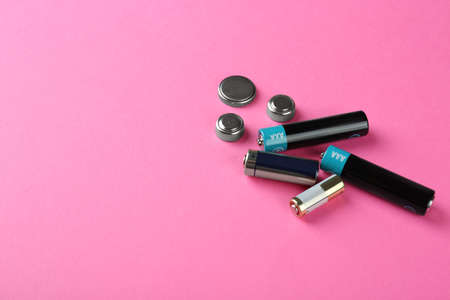 Different types of batteries on pink background, space for text