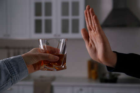 Man refusing to drink whiskey at home, closeup. Alcohol treatment addictionの写真素材