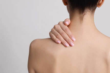 Back view of woman with perfect smooth skin on light background, closeup