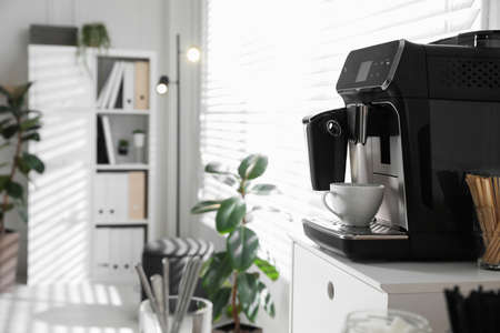 Modern coffee machine with cup in office. Space for textの写真素材