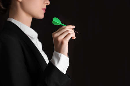Businesswoman holding green dart on black background, closeup. Space for textの写真素材