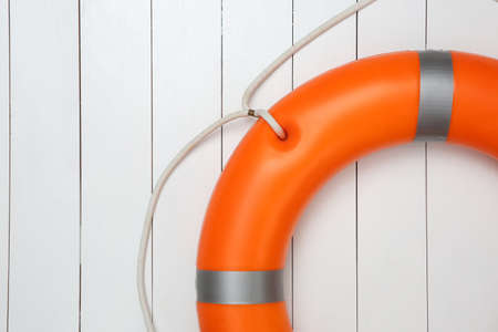 Orange lifebuoy on white wooden background, space for text. Rescue equipmentの写真素材