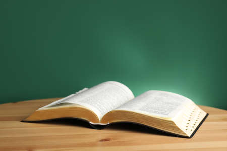 Open Bible on wooden table against green backgroundの写真素材