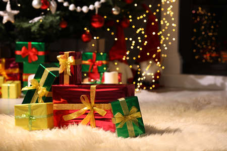 Beautiful gift boxes near Christmas tree in room, space for textの写真素材