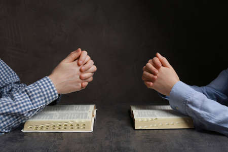 Couple praying over Bibles at gray table, closeupの写真素材