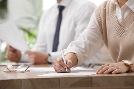 Woman signing contract at table in office, closeup.の写真素材