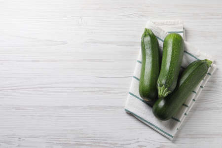 Raw ripe zucchinis on white wooden table, flat lay. Space for textの写真素材