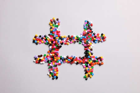 Hashtag symbol of colorful melty beads on light background, top viewの写真素材