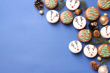 Beautifully decorated Christmas macarons on blue background, flat lay. Space for textの写真素材