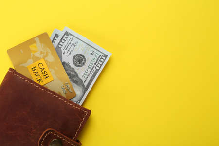 Dollar banknotes and credit card in wallet on yellow background, top view with space for text. cashback conceptの写真素材