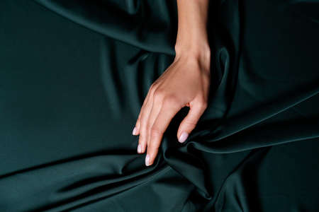Woman touching soft dark green fabric, top viewの写真素材