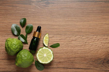Glass bottle of bergamot essential oil and fresh fruits on wooden table, flat lay. Space for textの写真素材