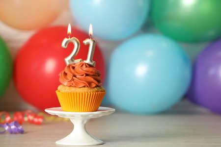 21th birthday, coming of age party. Delicious cupcake with number shaped candles on wooden table, space for textの写真素材