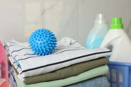 Blue dryer ball on stacked clean clothes near detergentsの写真素材