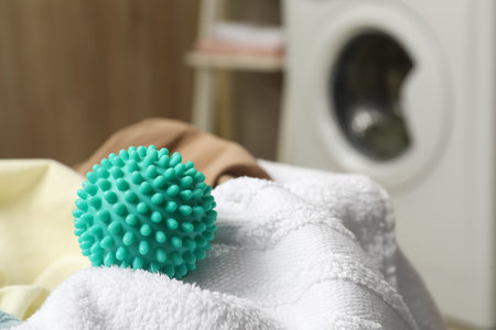 Turquoise dryer ball and towels near washing machine in laundry room, closeup. Space for textの写真素材