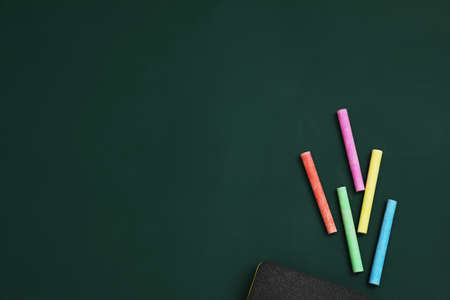 Colorful chalks and duster on green board, flat lay. Space for textの写真素材